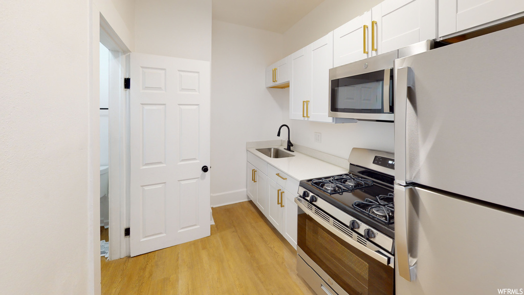 Kitchen featuring gas range oven, stainless steel microwave, refrigerator, and light hardwood floors