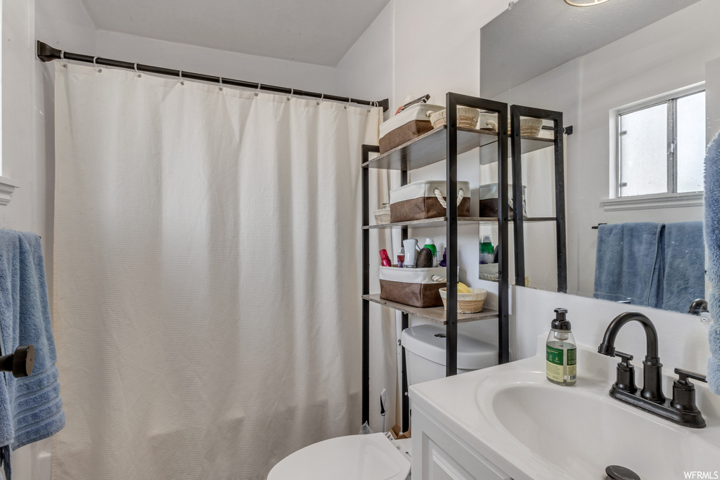 Bathroom featuring natural light, shower curtain, vanity, mirror, and toilet