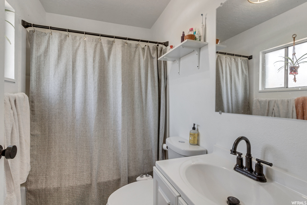 Bathroom with natural light, mirror, toilet, shower curtain, and vanity
