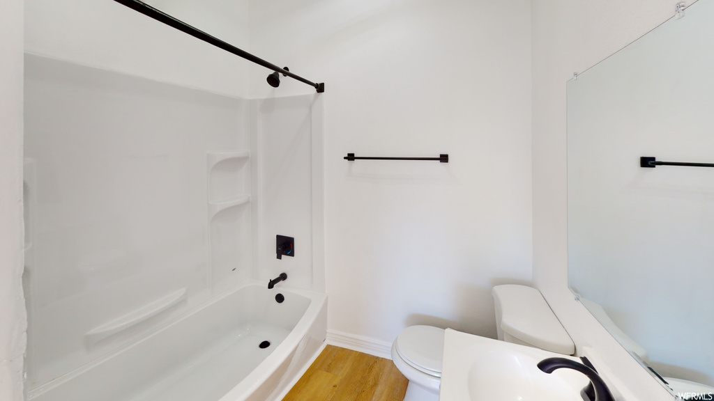Full bathroom featuring hardwood flooring, mirror, toilet, sink, and shower / bathtub combination
