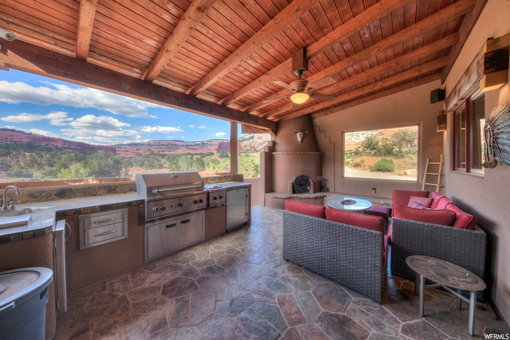 View of patio / terrace with an outdoor kitchen, an outdoor fireplace, and a ceiling fan