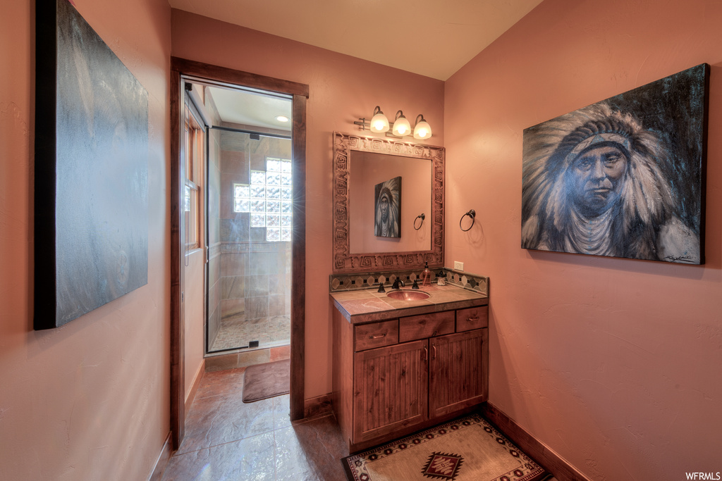Bathroom featuring tile floors, vanity, mirror, and shower with glass door