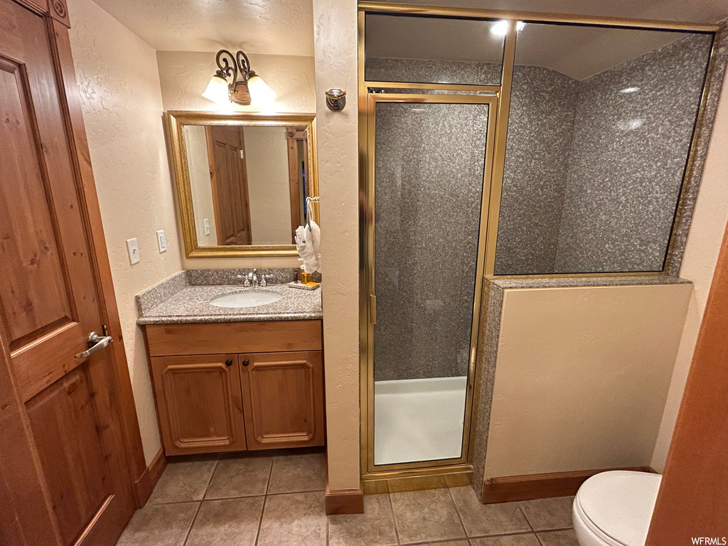 Full bathroom featuring tile flooring, vanity, toilet, shower booth, and multiple mirrors