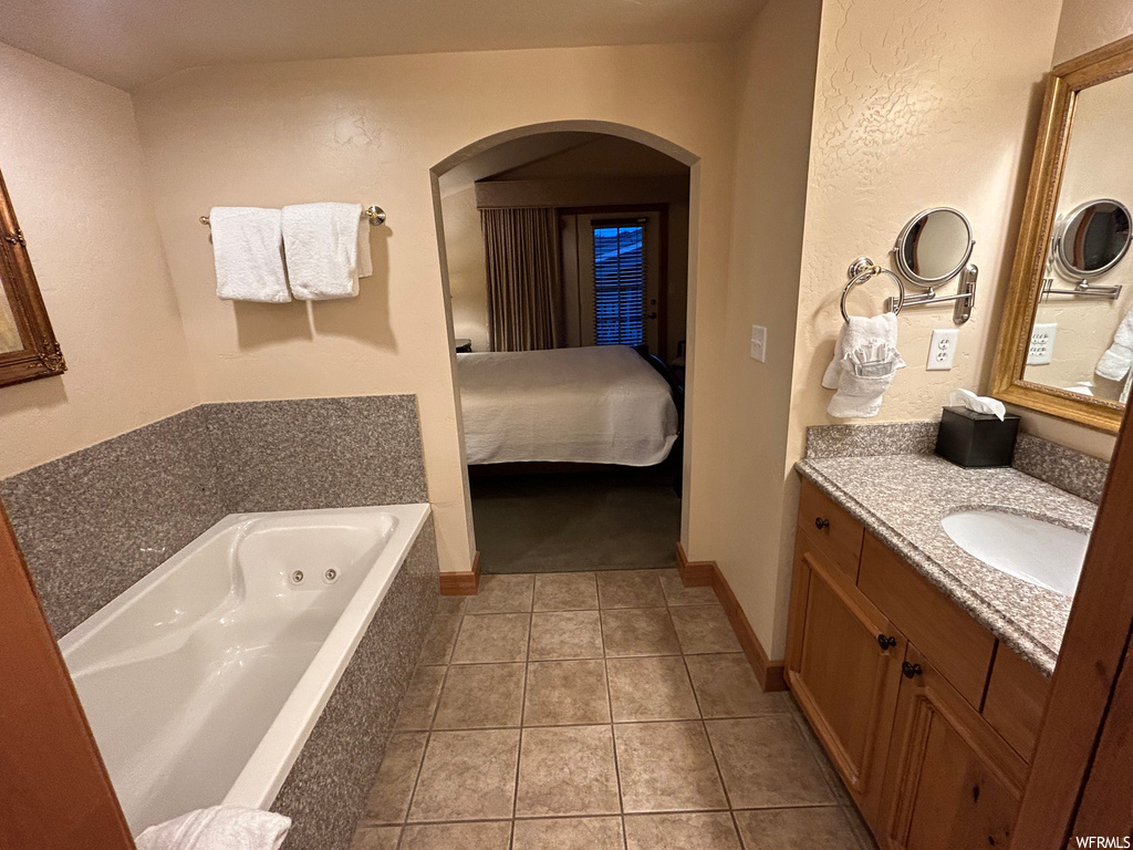 Bathroom featuring tile flooring, vanity, a bath, and mirror