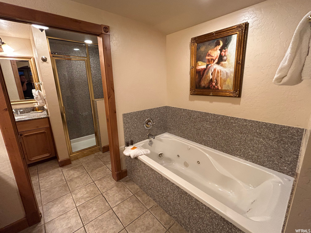 Bathroom with tile floors, vanity, mirror, and shower with separate bathtub