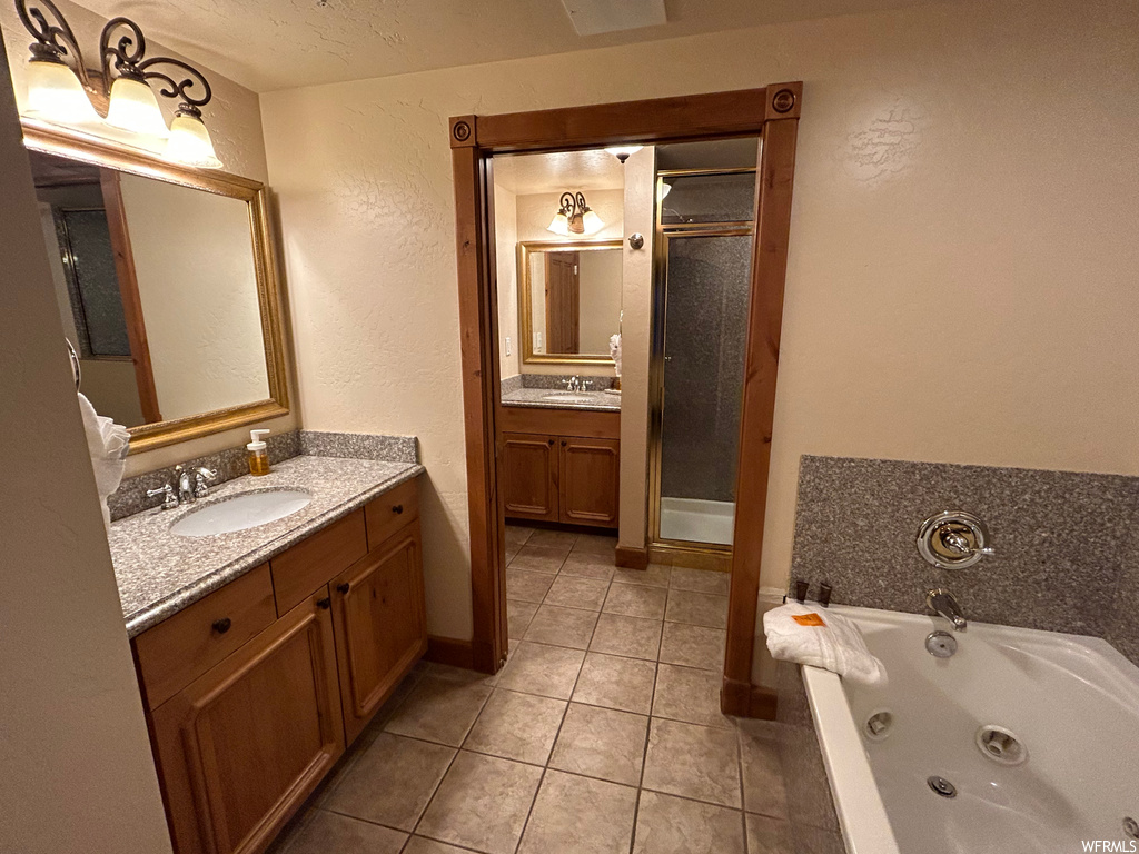 Bathroom with tile floors, a bathtub, double sink vanity, shower door, and multiple mirrors