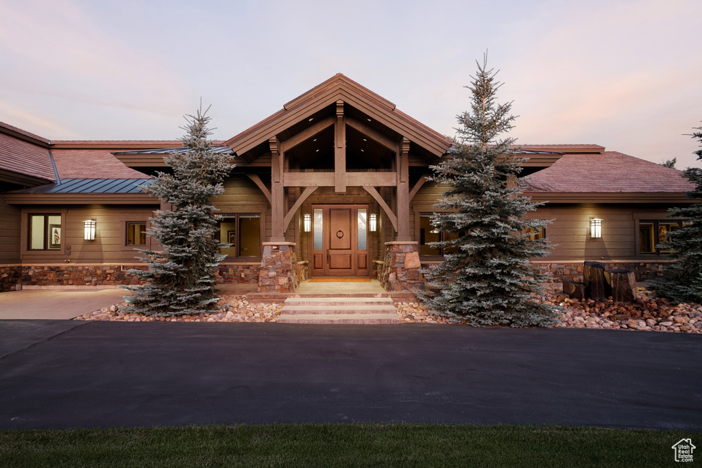 View of front facade with a standing seam roof, metal roof, and stone siding