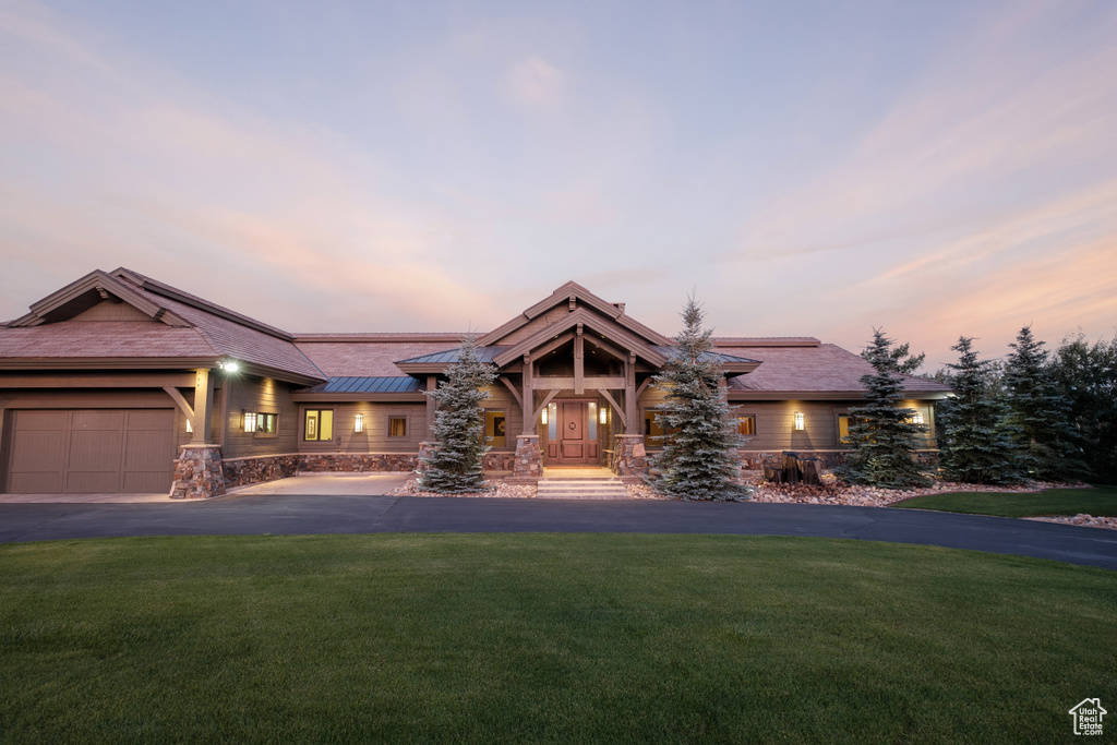 View of front of house with a garage, a front lawn, driveway, and stone siding