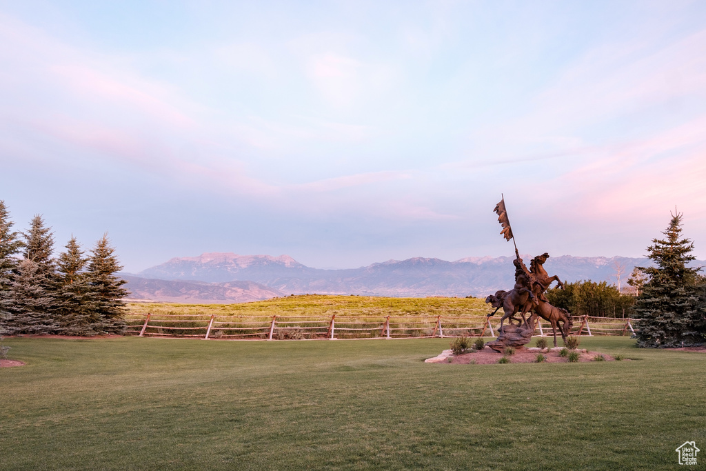 Yard at dusk with a mountain view, a rural view, and fence