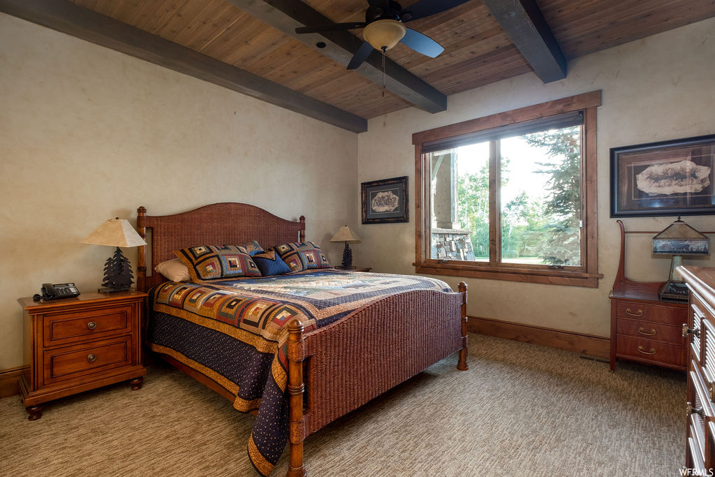 Bedroom featuring wood beam ceiling, carpet, and natural light
