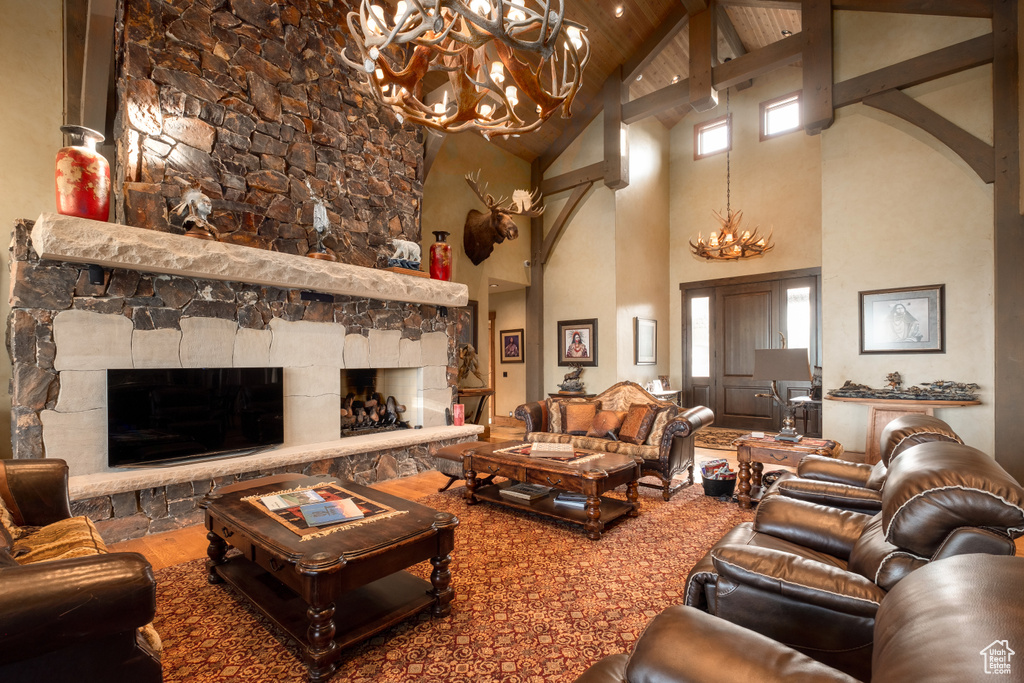 Living room featuring arched walkways, a fireplace, beam ceiling, high vaulted ceiling, and a notable chandelier