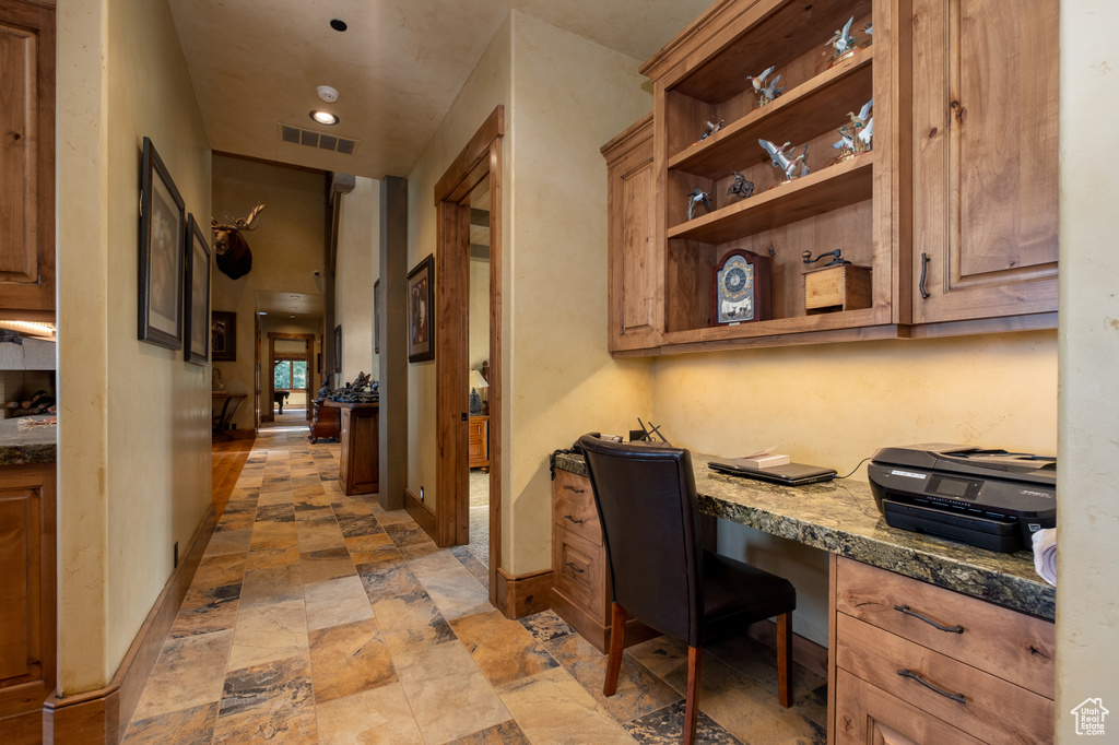 Home office with visible vents, built in study area, baseboards, recessed lighting, and stone finish flooring