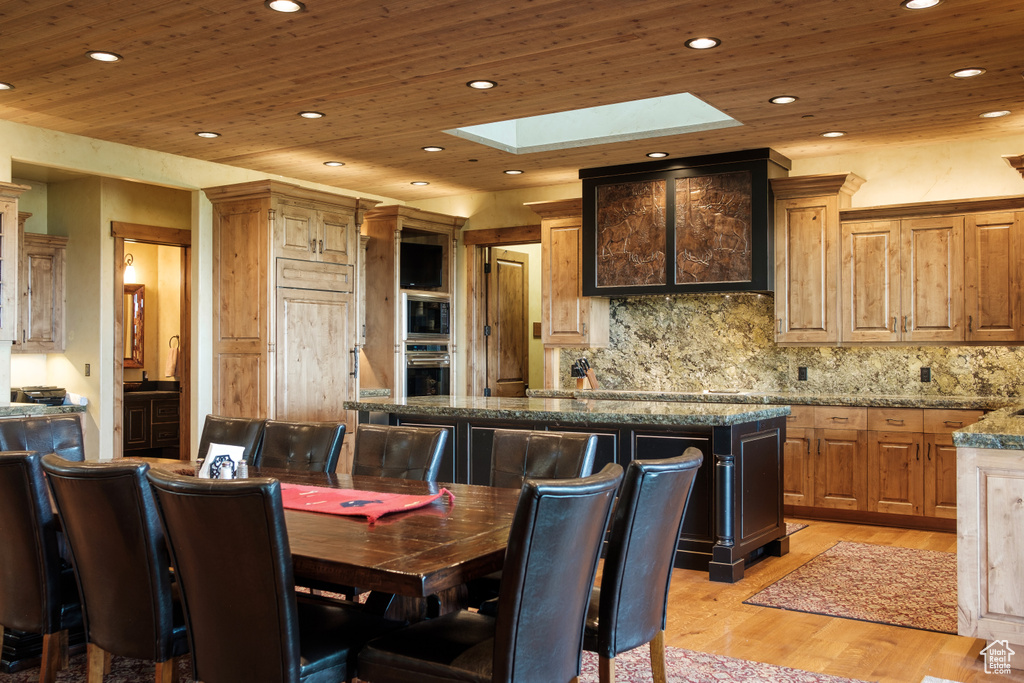 Dining space with a skylight, wooden ceiling, light wood finished floors, and recessed lighting