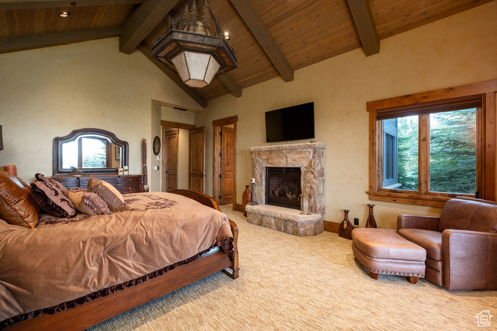 Carpeted bedroom with lofted ceiling with beams, wooden ceiling, and a fireplace