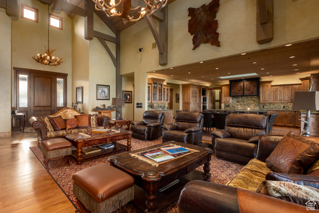 Living area with light wood-style floors, recessed lighting, a towering ceiling, and a notable chandelier