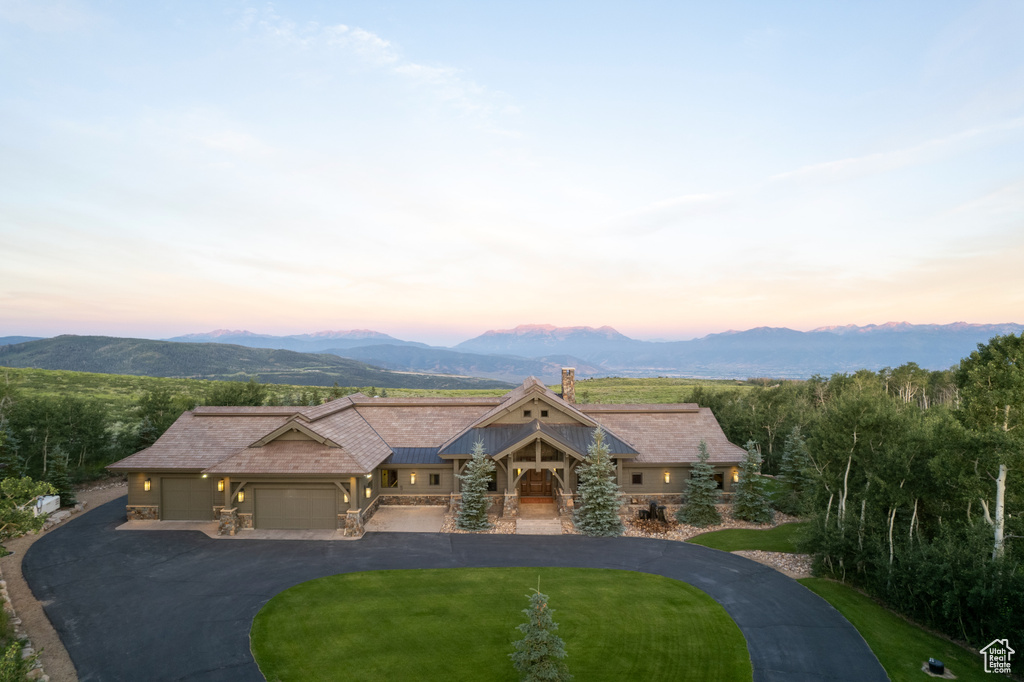View of front of house with a garage, a mountain view, a chimney, and driveway
