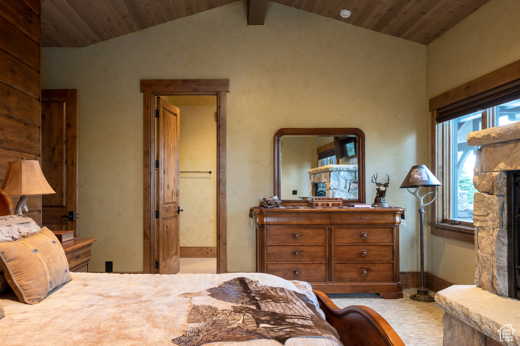 Bedroom featuring ensuite bath, lofted ceiling, a fireplace, and wooden ceiling