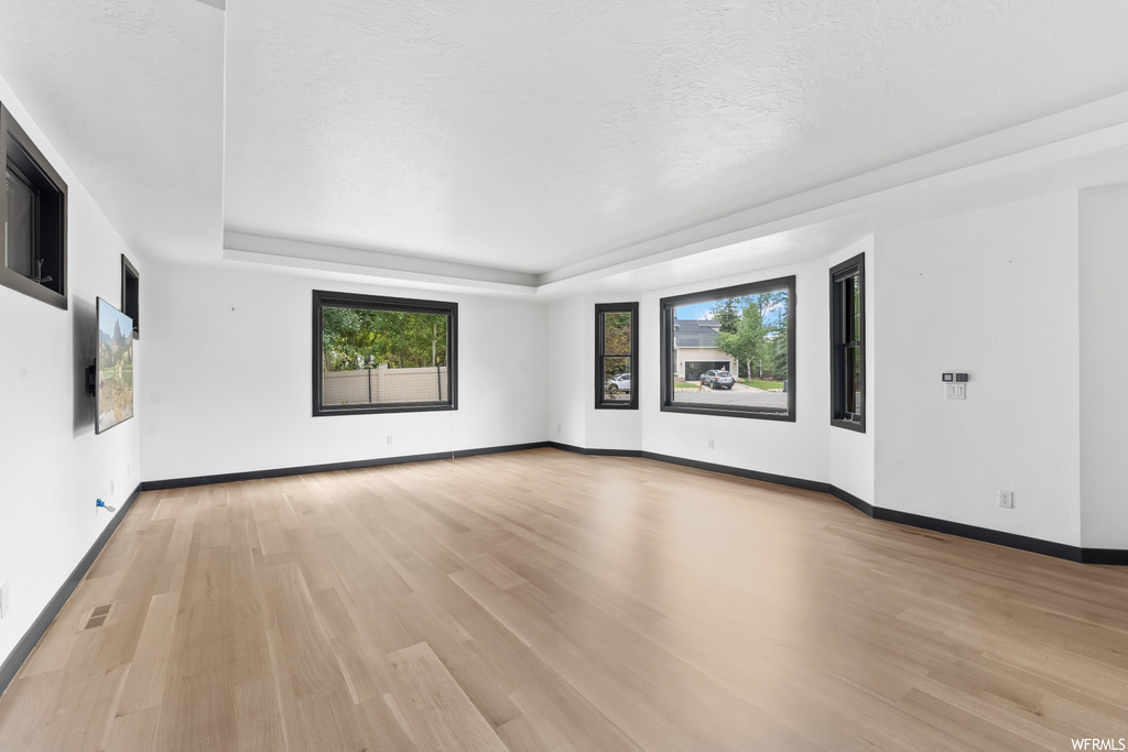 Wood floored empty room featuring natural light