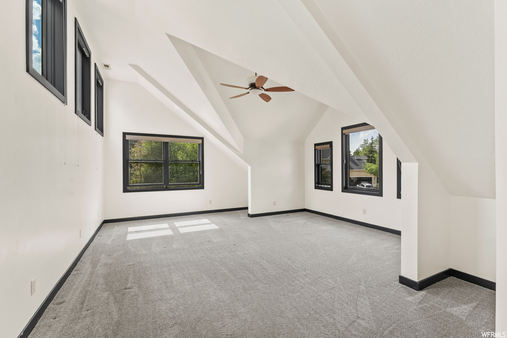 Additional living space featuring vaulted ceiling, plenty of natural light, a ceiling fan, and carpet