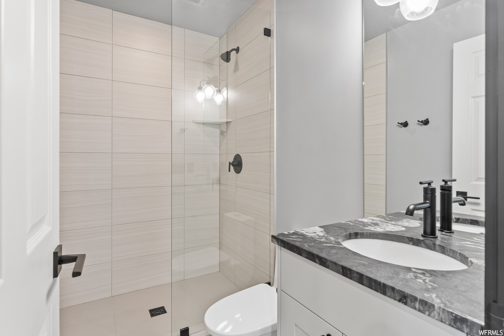 Bathroom featuring large vanity, a shower, mirror, and toilet