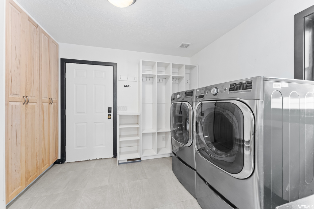 Washroom with tile flooring and independent washer and dryer