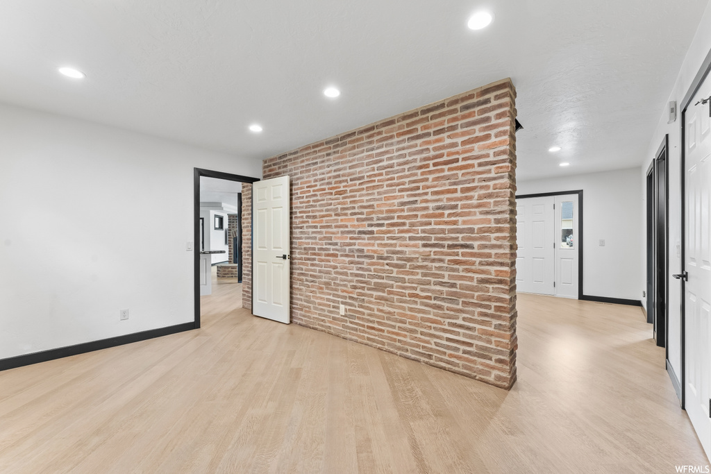 Empty room featuring exposed bricks and hardwood floors