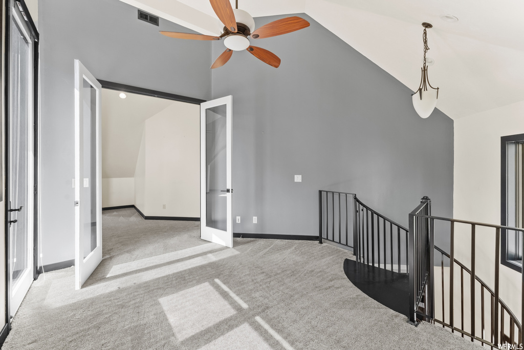 Spare room with vaulted ceiling, a ceiling fan, and carpet