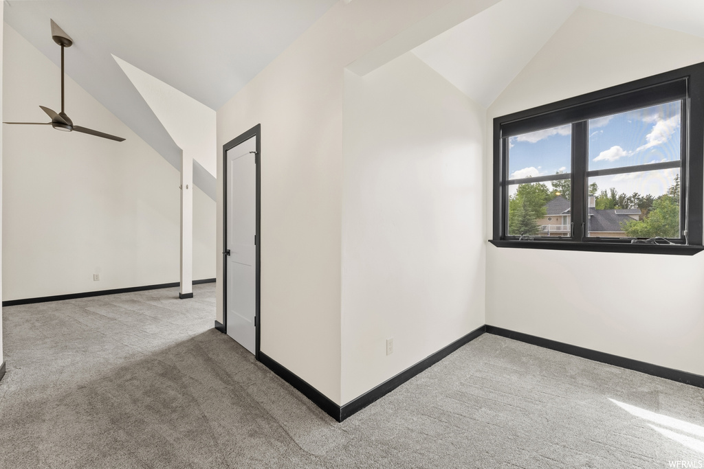 Carpeted spare room with vaulted ceiling and natural light