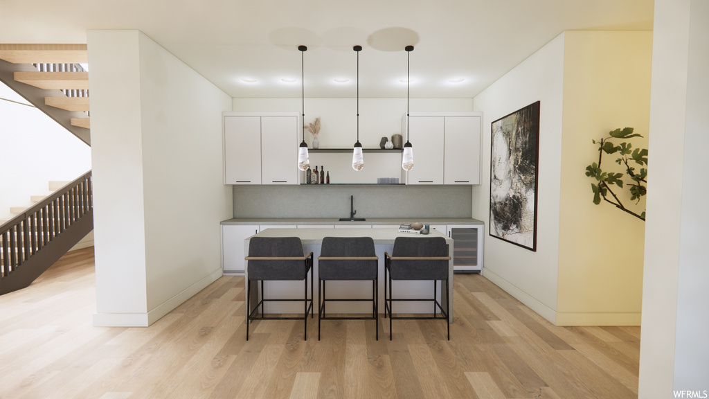 Kitchen with light parquet floors, white cabinets, and pendant lighting