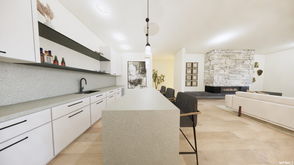 Kitchen featuring a fireplace, light tile flooring, white cabinets, light granite-like countertops, and pendant lighting