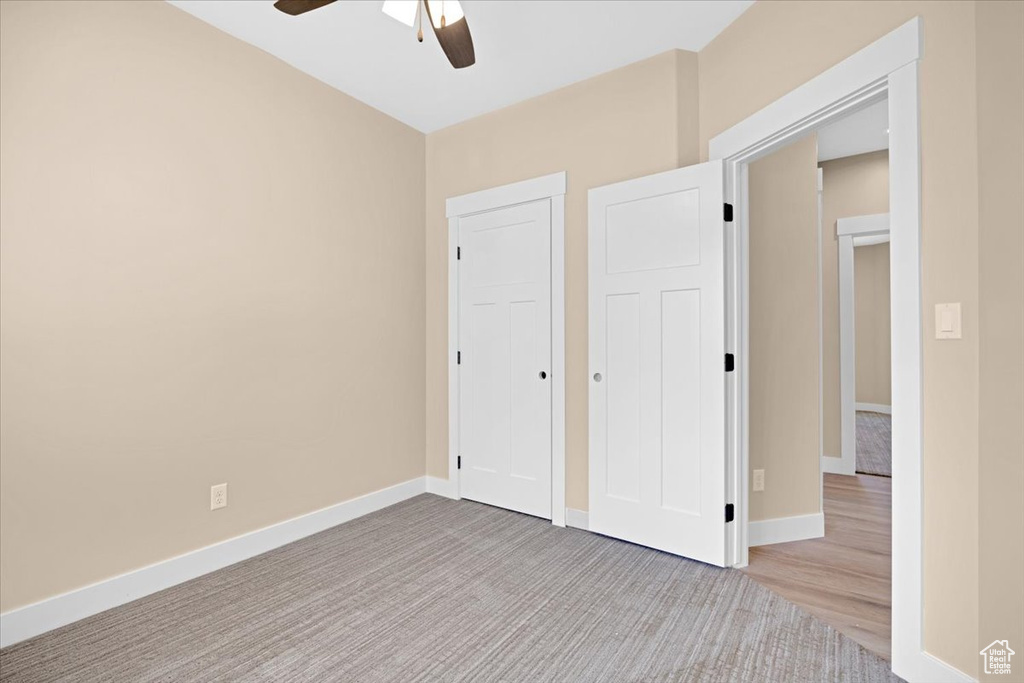 Unfurnished bedroom featuring hardwood / wood-style floors, a closet, and ceiling fan