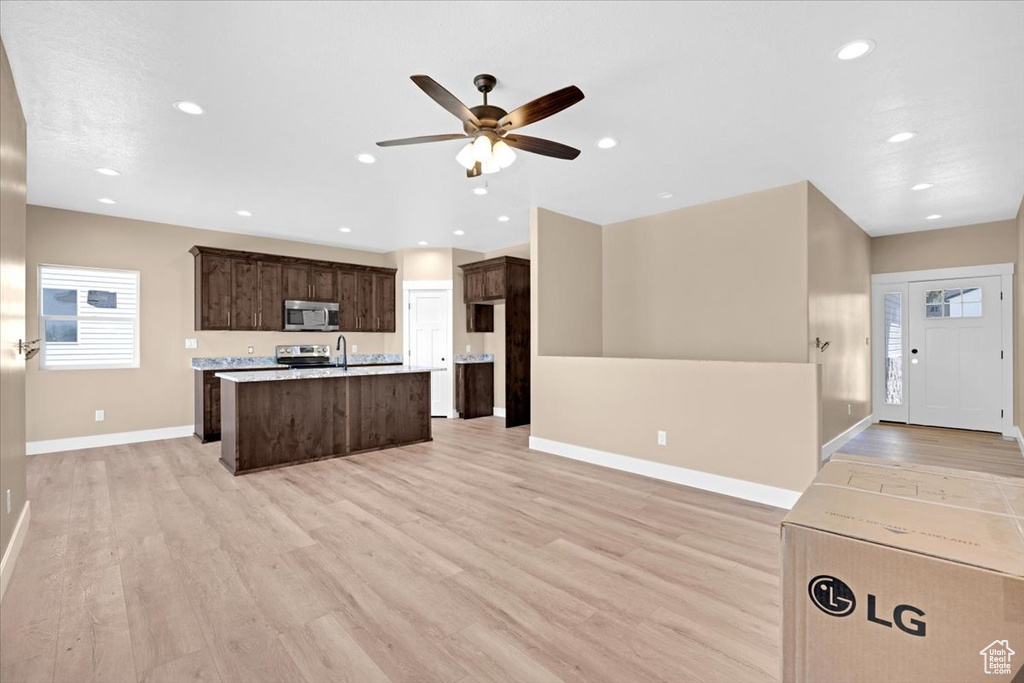 Kitchen featuring dark brown cabinetry, range, light hardwood / wood-style flooring, a center island with sink, and ceiling fan