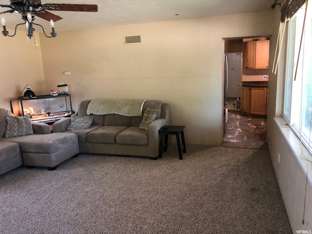 Carpeted living room featuring a ceiling fan