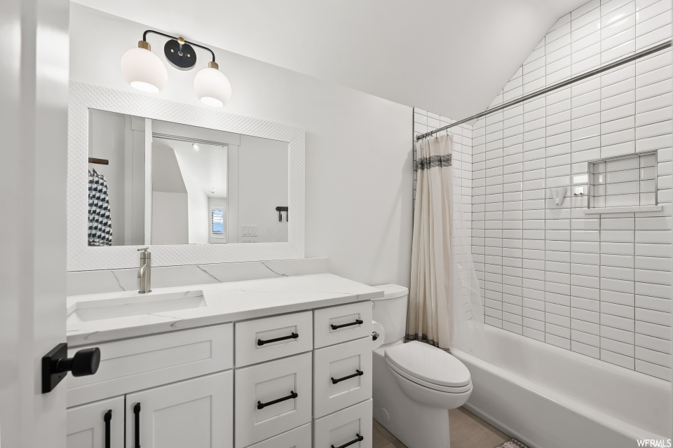 Full bathroom featuring oversized vanity, tile flooring, vaulted ceiling, mirror, and shower / bath combo