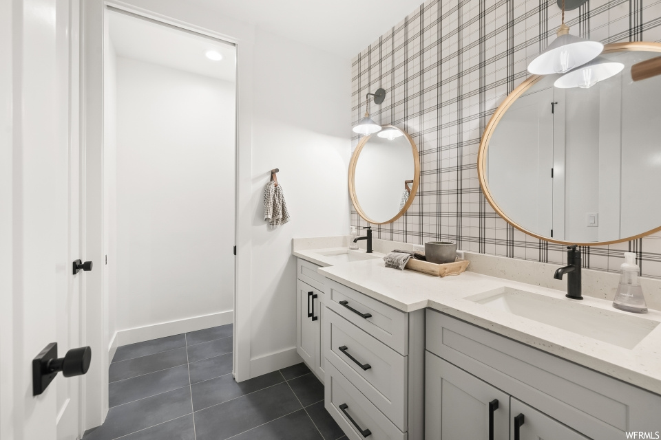 Bathroom featuring mirror, dark tile floors, double vanity, and backsplash