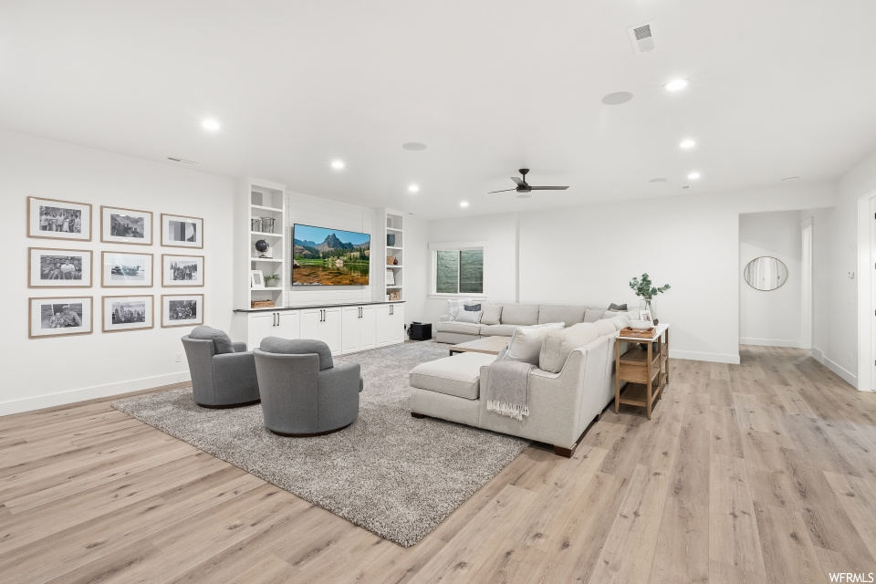 Living room with ceiling fan, light parquet floors, and TV