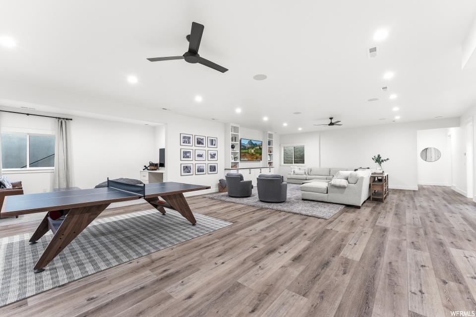 Living room featuring a ceiling fan, hardwood flooring, and natural light