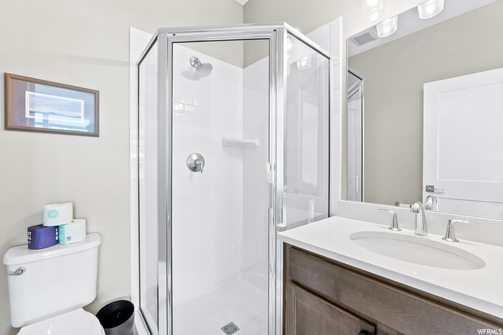 Full bathroom with large vanity, shower with shower door, mirror, and toilet