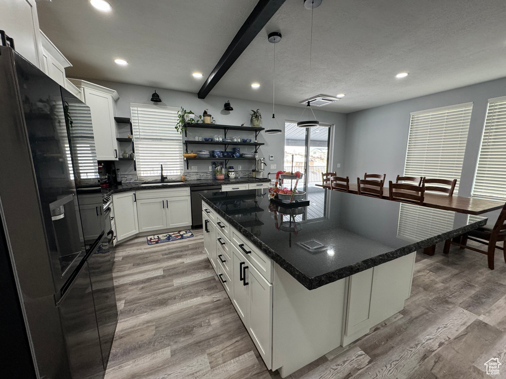 Kitchen featuring white cabinets, sink, light hardwood / wood-style floors, and a kitchen island