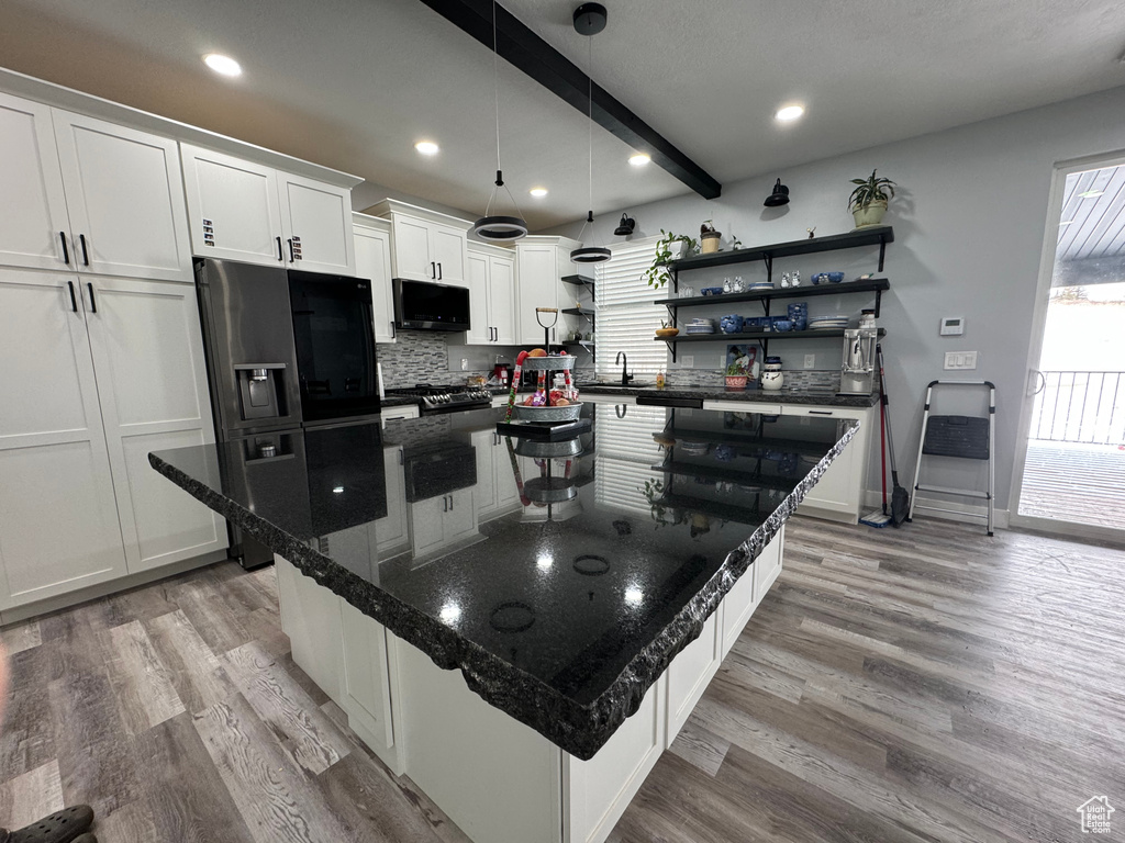 Kitchen with black appliances, light hardwood / wood-style flooring, white cabinets, and a center island