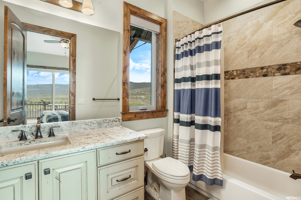 Full bathroom featuring natural light, shower curtain, vanity, bathtub / shower combination, mirror, and toilet