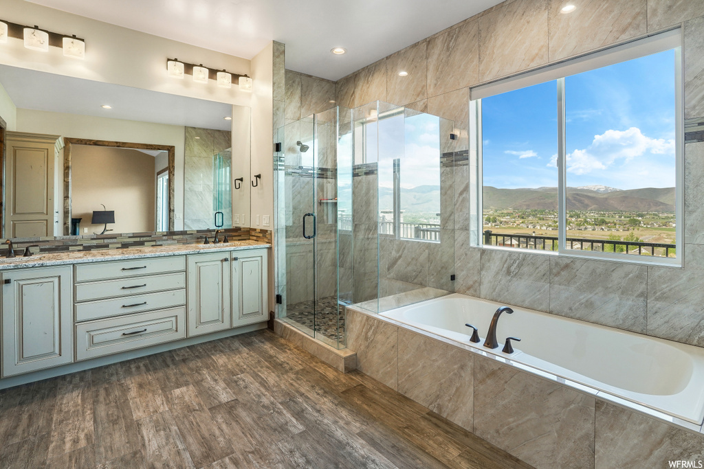 Bathroom featuring hardwood floors, natural light, dual vanity, mirror, and independent shower and bath