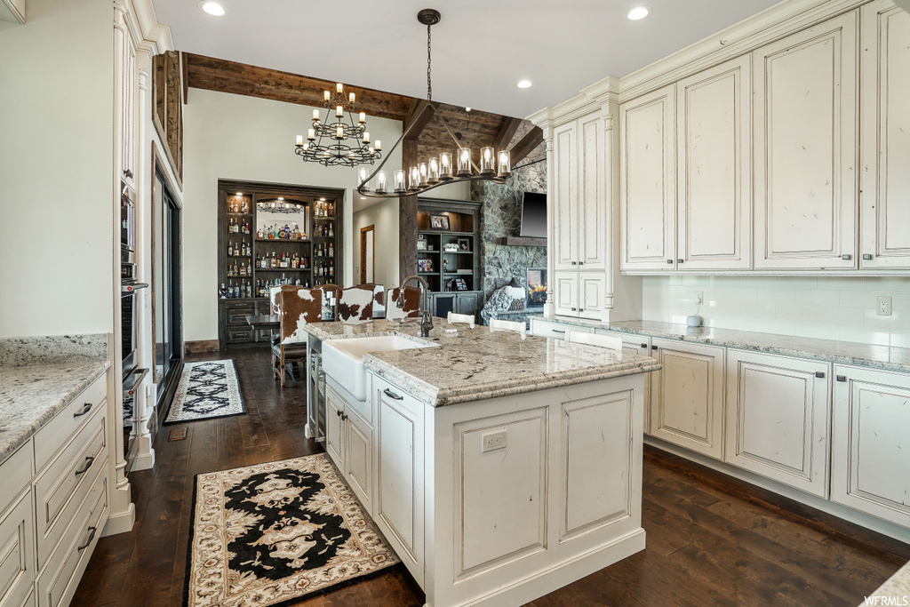 Kitchen featuring a kitchen island, a chandelier, dark parquet floors, pendant lighting, white cabinets, and light granite-like countertops