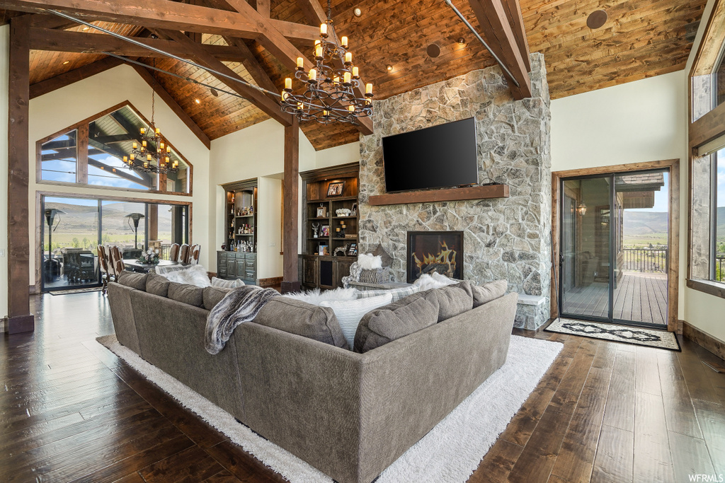 Hardwood floored living room with natural light, a fireplace, a high ceiling, lofted ceiling, a chandelier, and TV