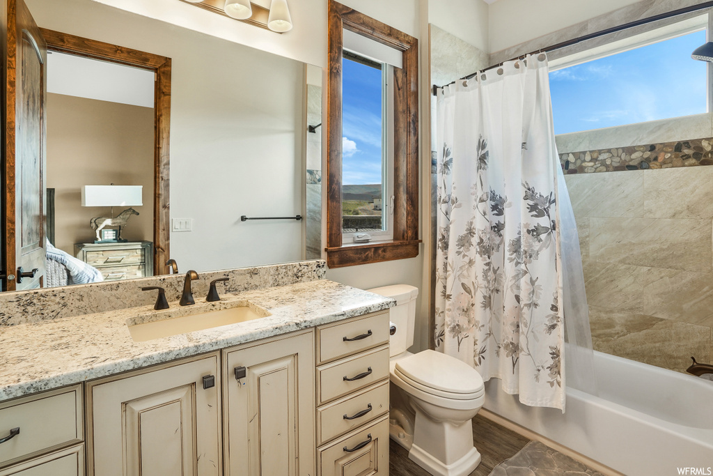 Full bathroom featuring shower / washtub combination, toilet, mirror, shower curtain, and vanity