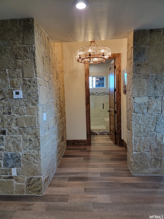 Hallway with a chandelier and hardwood flooring