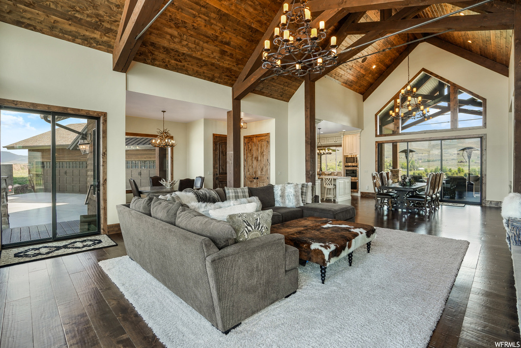 Living room featuring a high ceiling, natural light, a notable chandelier, vaulted ceiling with beams, and hardwood floors