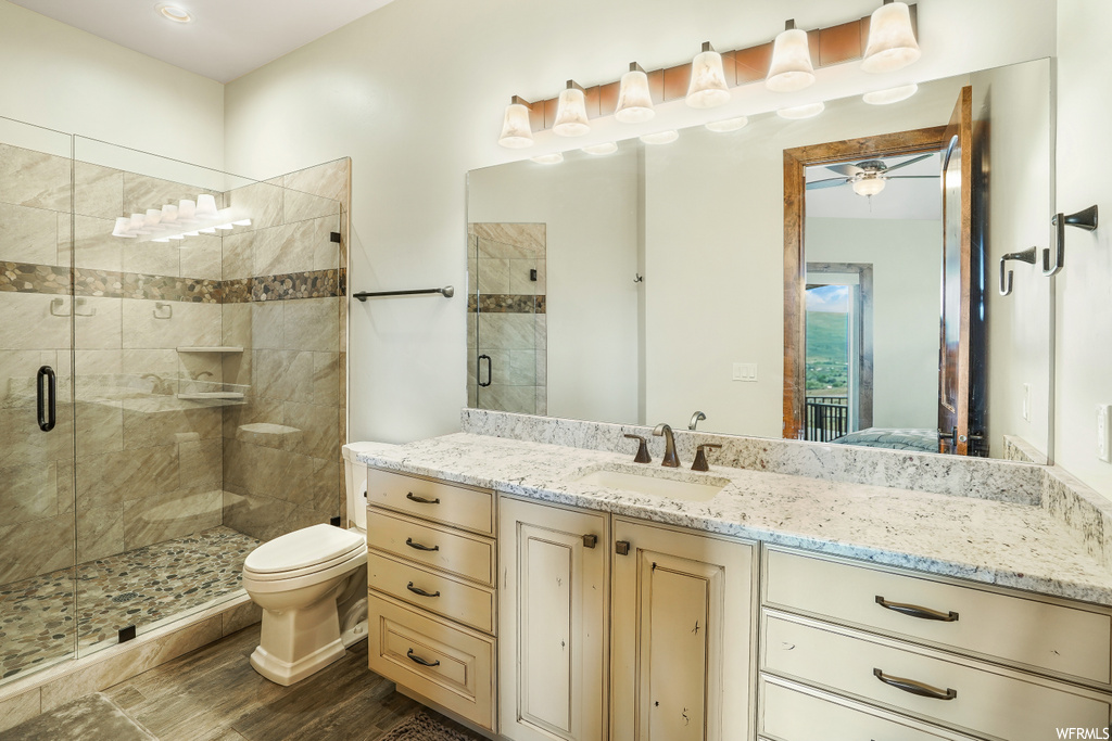 Full bathroom featuring mirror, toilet, vanity, and shower with glass door