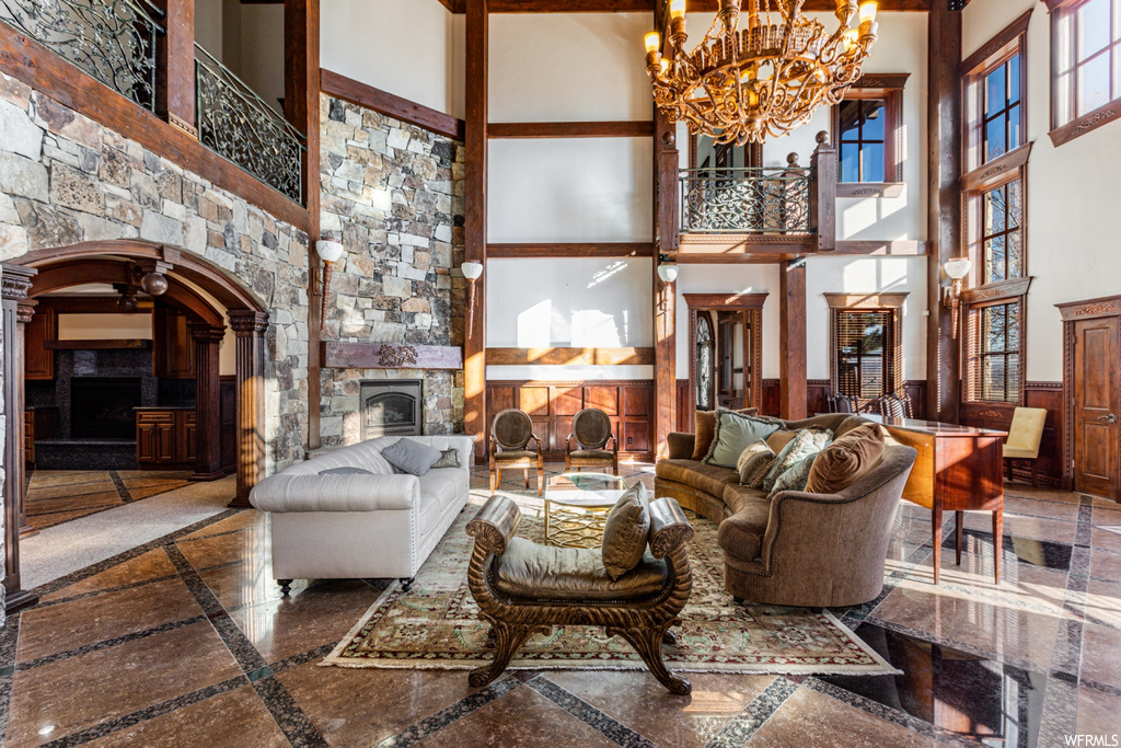 Tiled living room featuring an inviting chandelier, a towering ceiling, and a fireplace