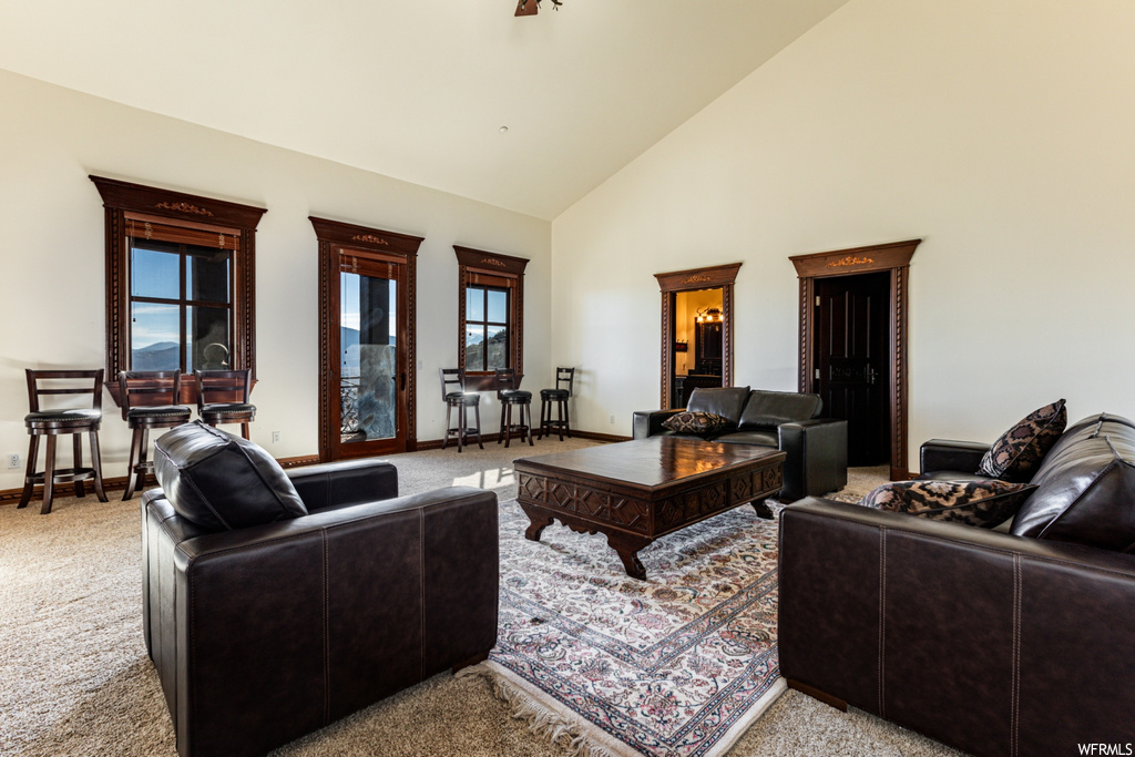 Living room featuring light colored carpet, plenty of natural light, and high vaulted ceiling